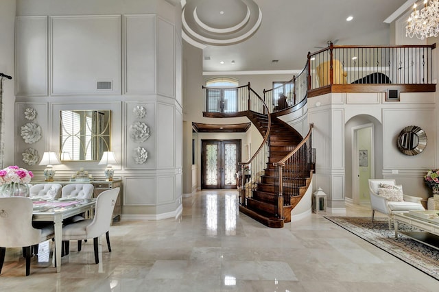 entryway featuring ornamental molding, french doors, a high ceiling, and an inviting chandelier