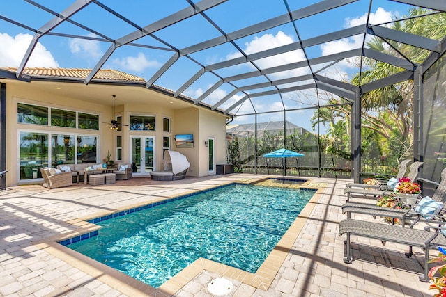 view of pool featuring a patio area, ceiling fan, glass enclosure, and an outdoor hangout area