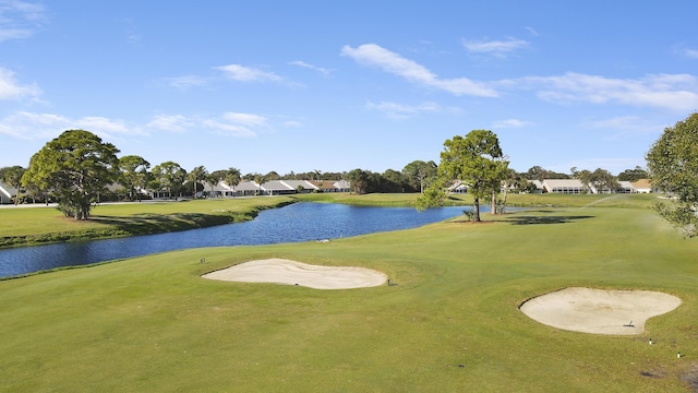 view of community featuring a water view, a lawn, and golf course view