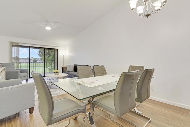 dining room with vaulted ceiling, light wood finished floors, ceiling fan with notable chandelier, and baseboards