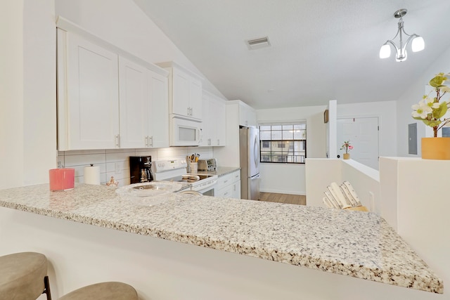 kitchen with kitchen peninsula, a breakfast bar area, white appliances, white cabinets, and pendant lighting