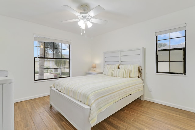 bedroom with ceiling fan, light wood-type flooring, and baseboards