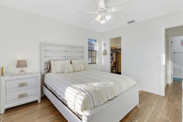 bedroom featuring visible vents, a spacious closet, baseboards, and wood finished floors