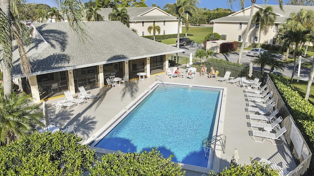 community pool with a sunroom, a patio area, and fence