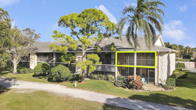 view of side of home featuring a sunroom, dirt driveway, and a yard