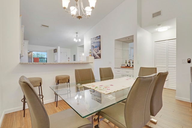 dining area featuring vaulted ceiling, a notable chandelier, and light hardwood / wood-style floors