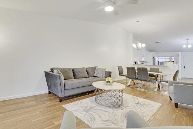 living area with light wood finished floors, baseboards, vaulted ceiling, and ceiling fan with notable chandelier