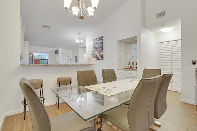 dining room featuring visible vents, an inviting chandelier, light wood-style floors, high vaulted ceiling, and baseboards