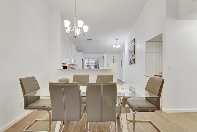 dining room with baseboards, visible vents, light wood finished floors, and an inviting chandelier