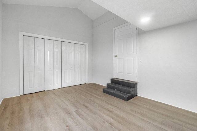 unfurnished bedroom with light wood-type flooring and lofted ceiling