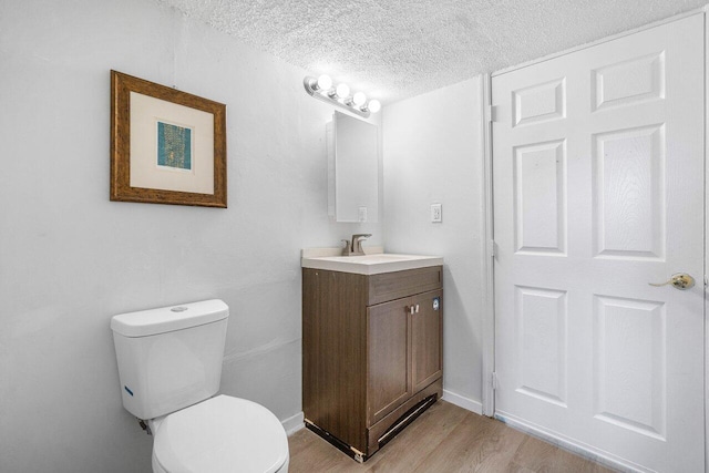 bathroom with hardwood / wood-style floors, vanity, a textured ceiling, and toilet