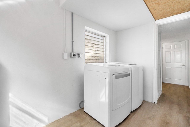 clothes washing area with washer and dryer and light wood-type flooring