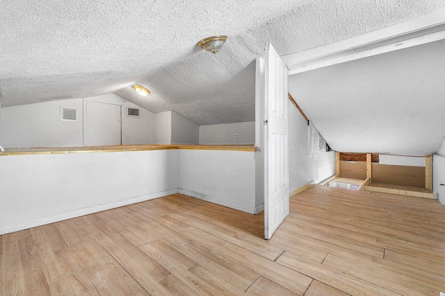 additional living space featuring lofted ceiling and light wood-type flooring