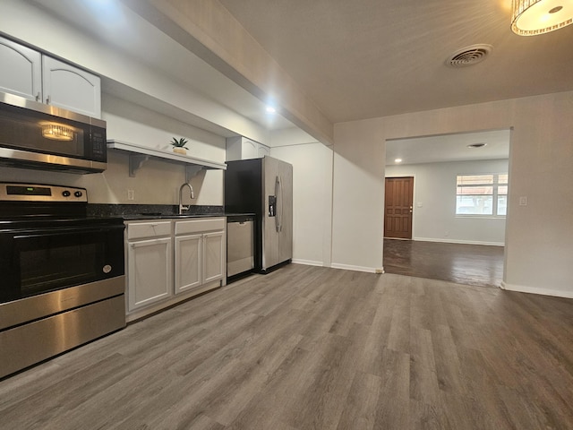 kitchen with appliances with stainless steel finishes, light hardwood / wood-style flooring, white cabinetry, and sink