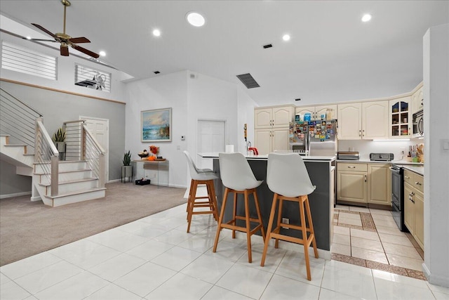 kitchen with appliances with stainless steel finishes, a center island, light colored carpet, and cream cabinets