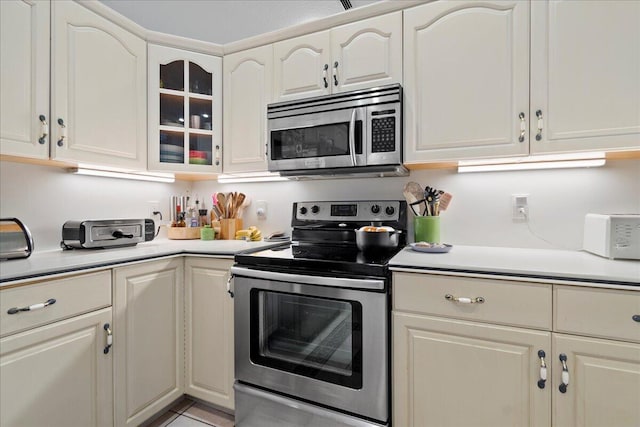 kitchen with cream cabinetry, stainless steel appliances, and light tile patterned flooring