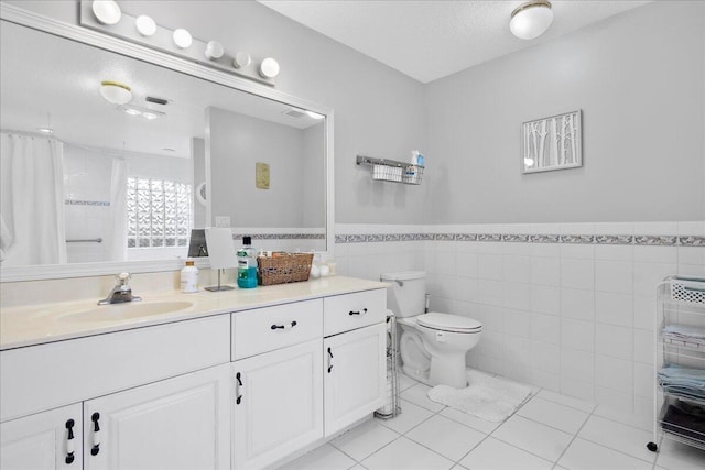 bathroom featuring tile patterned floors, a textured ceiling, toilet, vanity, and tile walls