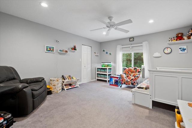 recreation room with ceiling fan and light carpet