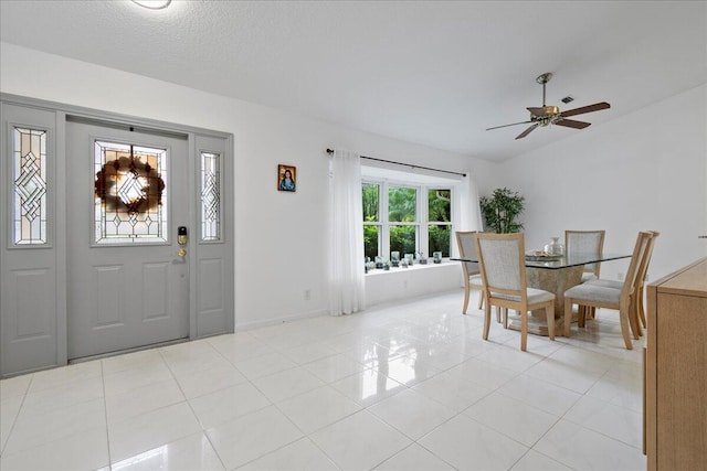 foyer entrance featuring ceiling fan, light tile patterned floors, and a textured ceiling