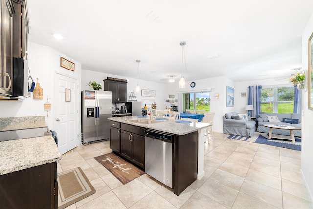 kitchen with appliances with stainless steel finishes, a center island with sink, dark brown cabinets, and pendant lighting