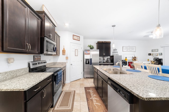 kitchen with stainless steel appliances, sink, pendant lighting, a center island with sink, and light tile patterned flooring