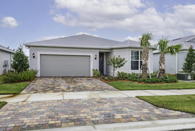 ranch-style home with a garage, a shingled roof, decorative driveway, and stucco siding