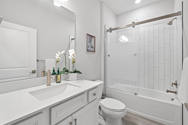 full bathroom featuring wood-type flooring, toilet, vanity, and tiled shower / bath