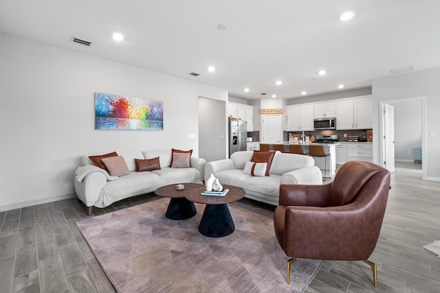 living area featuring light wood-style floors, recessed lighting, and visible vents