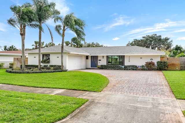 ranch-style home with a garage and a front lawn