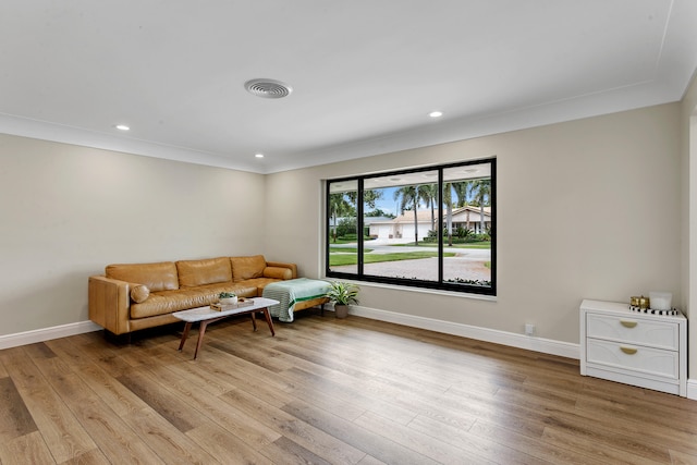 living room with light wood-type flooring and ornamental molding