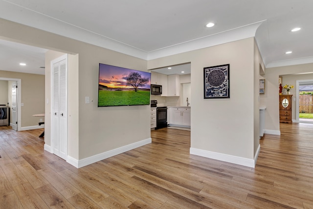 interior space with ornamental molding, sink, light hardwood / wood-style flooring, and independent washer and dryer