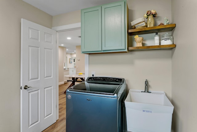 laundry room featuring cabinets, light hardwood / wood-style floors, sink, and washer / clothes dryer