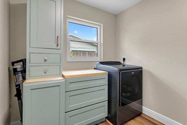 washroom with light hardwood / wood-style floors, cabinets, and washer and dryer