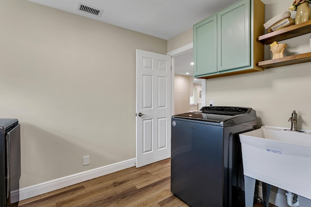 washroom featuring cabinets, sink, light hardwood / wood-style flooring, and independent washer and dryer