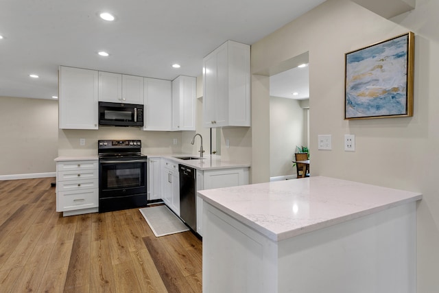 kitchen with black appliances, light stone countertops, light hardwood / wood-style floors, and white cabinets