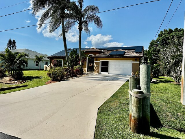 view of front of property featuring a garage, solar panels, and a front yard