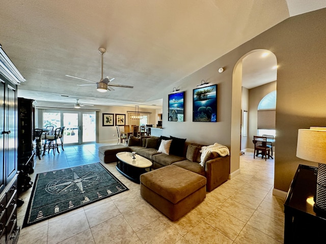 living room featuring baseboards, arched walkways, a ceiling fan, lofted ceiling, and light tile patterned flooring