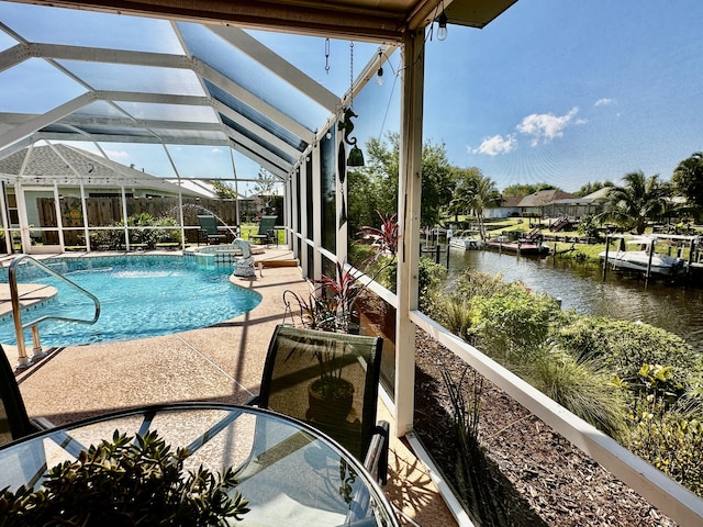 view of pool featuring a pool with connected hot tub, glass enclosure, a patio area, and a water view