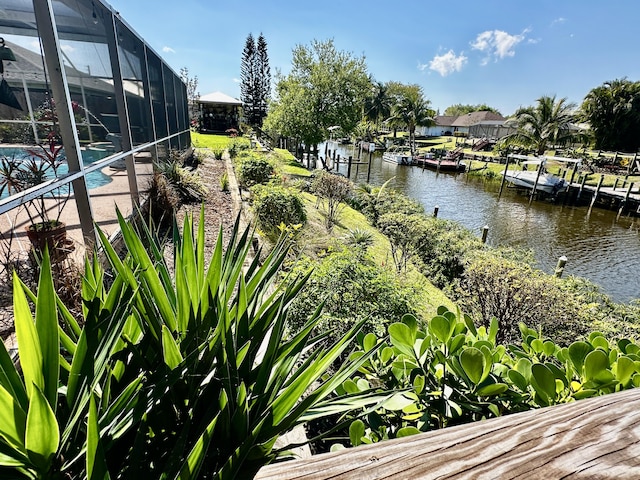 exterior space with a lanai, a water view, an outdoor pool, and a boat dock