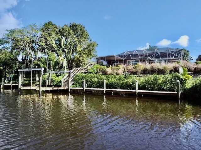 view of dock with a water view and glass enclosure