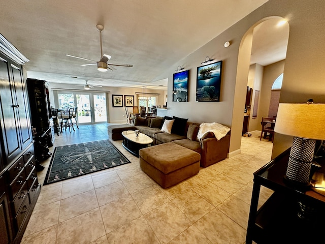 living room featuring light tile patterned floors, ceiling fan, arched walkways, and french doors