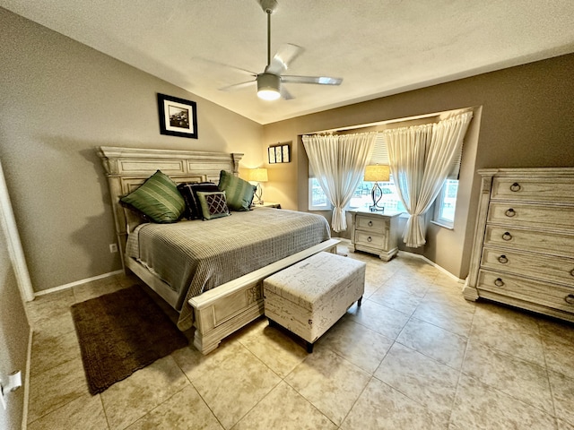 bedroom with light tile patterned floors, a ceiling fan, vaulted ceiling, a textured ceiling, and baseboards