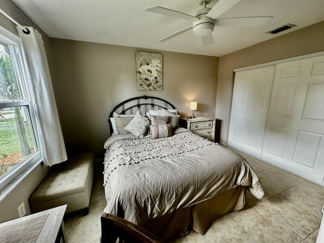 bedroom featuring ceiling fan, a closet, visible vents, and tile patterned floors