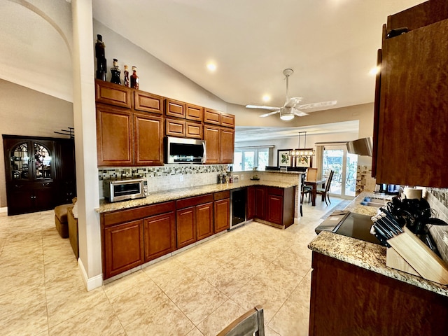 kitchen with beverage cooler, a peninsula, backsplash, light stone countertops, and stainless steel microwave