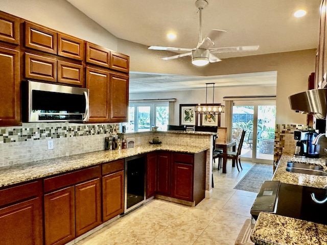 kitchen with wine cooler, stainless steel microwave, backsplash, a sink, and a peninsula