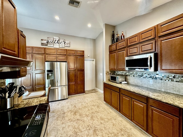 kitchen featuring appliances with stainless steel finishes, light stone countertops, visible vents, and decorative backsplash