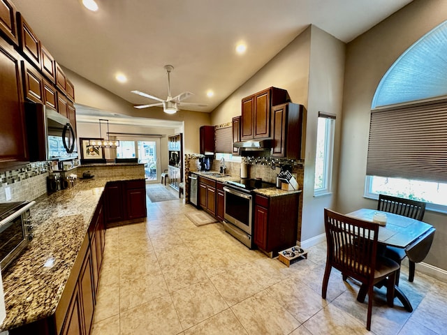 kitchen featuring lofted ceiling, light stone counters, under cabinet range hood, stainless steel appliances, and a peninsula