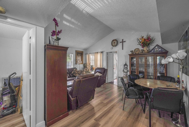 dining space featuring lofted ceiling, a textured ceiling, and wood-type flooring