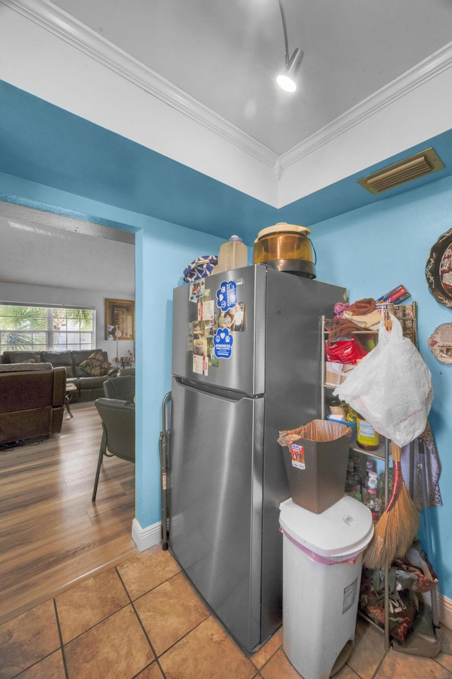 kitchen featuring tile patterned floors, crown molding, and stainless steel refrigerator