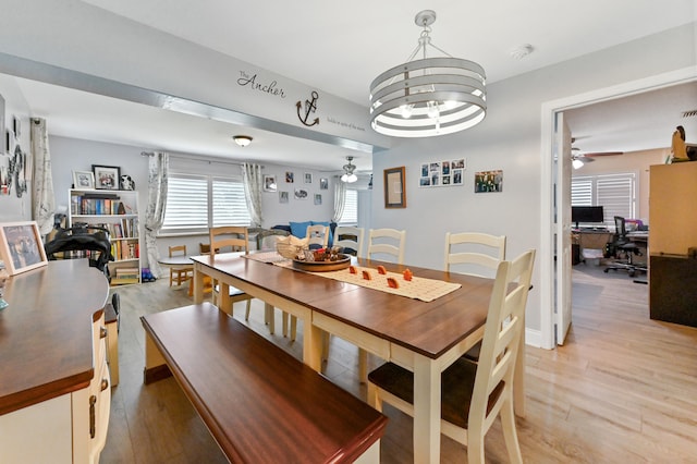 dining area featuring light wood-type flooring and ceiling fan with notable chandelier